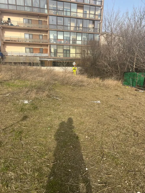 Teren viran curatat de vegetatie nedorita, langa un bloc de locuinte